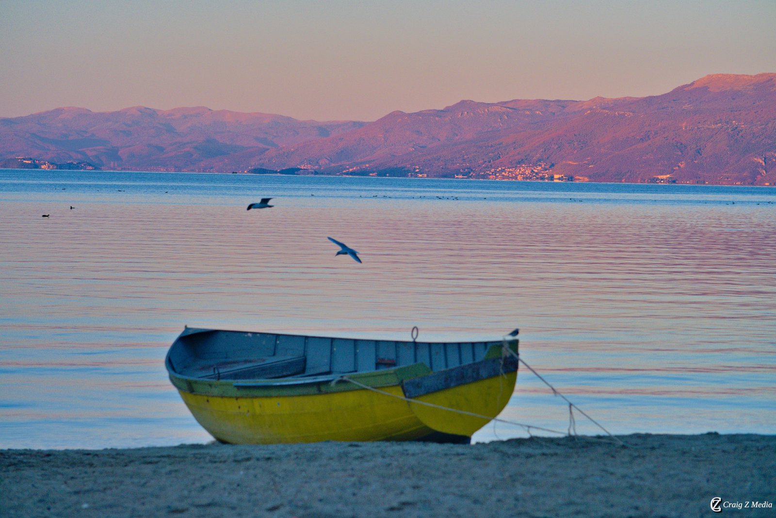 A traditional wooden boat resting on the pebbled shore of Lake Ohrid near Pogradec